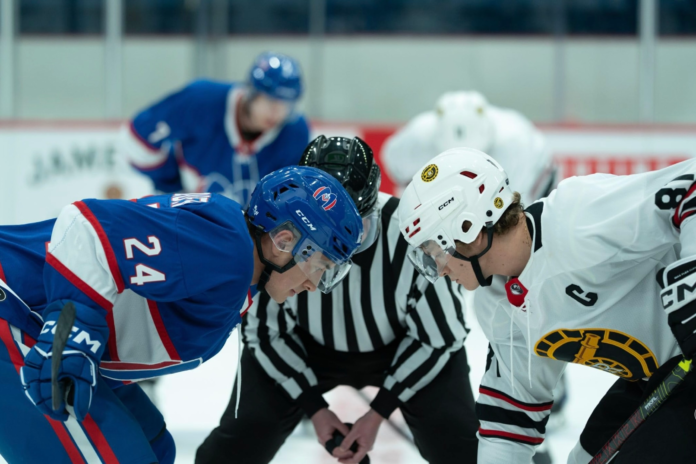 Two hockey players face off in a rink.