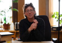 Q&A: Professor and philosopher explains how work, toxicity and disability affect day-to-day lives A person sits in an office with a stack of books on their desk and plants in the background.