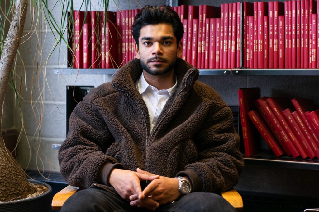 Aryan Singh poses for a photo in front of a book case
