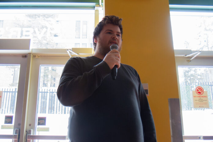 Maxwell Heroux speaks on a microphone
