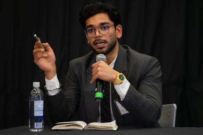 Aryan Singh holds a microphone while speaking at the CUSA presidential debate.
