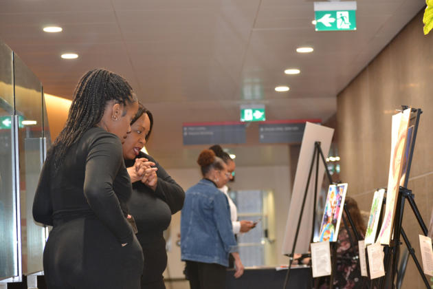 A few people look at art sitting on a stand.