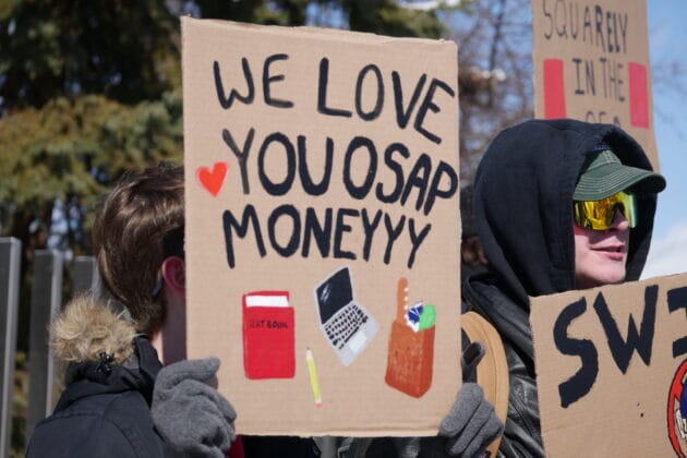 Person holding a sign that reads "We love you OSAP money"