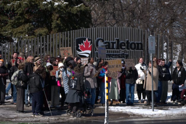 People gathered in front of the Carleton University sign