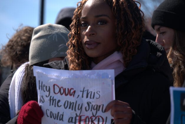 Person holding a sign that reads "Hey Doug, This is the only sign you could afford"