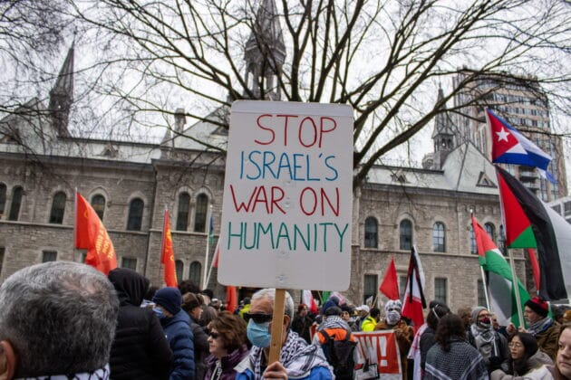 Person holding sign at a protest that reads "Stop Israels War On Humanity"