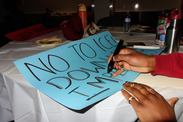 A hand holds a marker and writes on a poster that says "No to Ice! Down with imperialism"