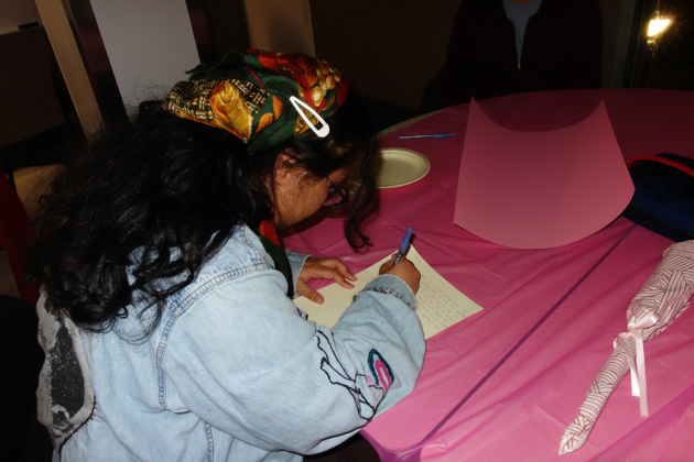 A person sits at a table and writes on a piece of paper.