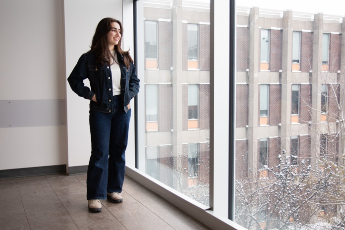 A standing woman looks out of a window.