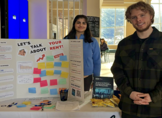 No Room for Students: How a CUSA report is highlighting student rent issues Two people stand at a table with a fold-out cardboard poster with sticky notes and a message that says "Let's talk about rent, your rent"