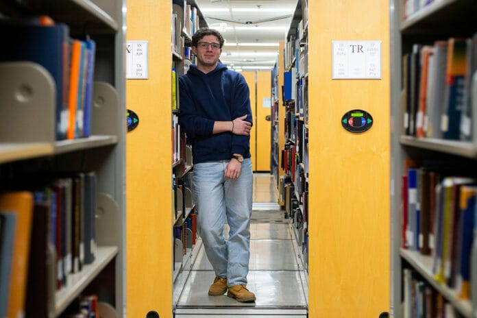 A man stands in between bookshelves