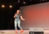 Carleton Linguavision participants bring diversity through song A woman wearing overalls holds a microphone up to her mouth as she stands on a stage.