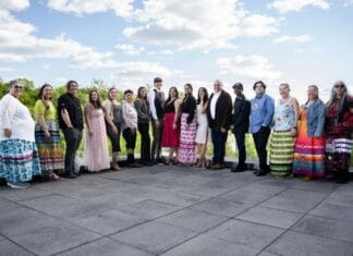 ‘We quickly became a family’: Carleton’s Indigenous journalism certificate wraps up its first year People line up outdoors on a concrete patio at Carleton University. There's a bright blue sky with the people standing and smiling across the frame.