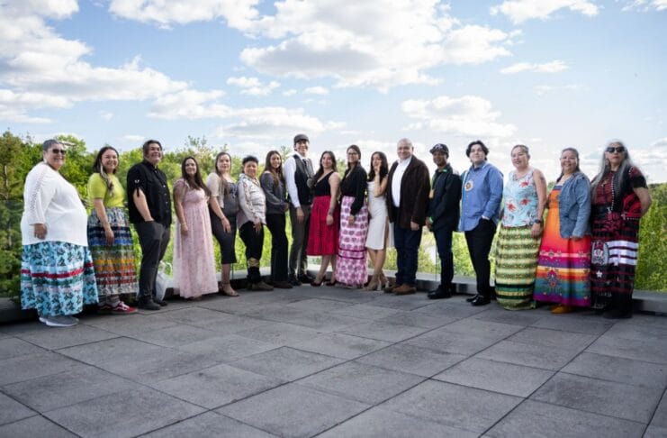 ‘We quickly became a family’: Carleton’s Indigenous journalism certificate wraps up its first year People line up outdoors on a concrete patio at Carleton University. There's a bright blue sky with the people standing and smiling across the frame.