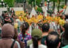 Ottawa’s largest Brazilian festival showcases cultural traditions and community spirit image displaying a crowd a people mostly dressed in yellow smiling and holding drums in front of an Ottawa sign in Ottawa.