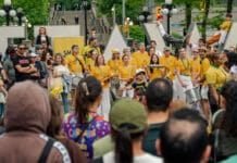 Ottawa’s largest Brazilian festival showcases cultural traditions and community spirit image displaying a crowd a people mostly dressed in yellow smiling and holding drums in front of an Ottawa sign in Ottawa.