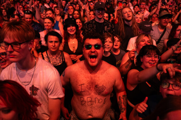 Man in sunglasses screams excited at camera in a crowd
