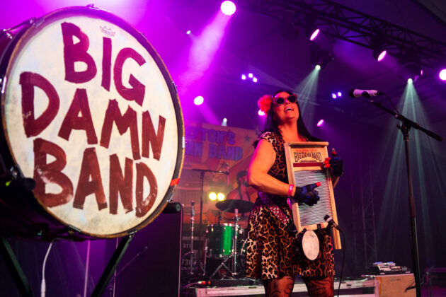 Woman smiles while playing washboard on stage