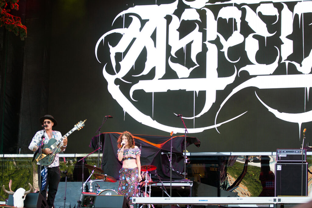 Man plays guitar while young woman sings on stage