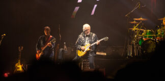 Bluesfest Day 9 review: The Guess Who closes Bluesfest with a powerful Canadian celebration Guy plays guitar on stage with other guitarist behind him.