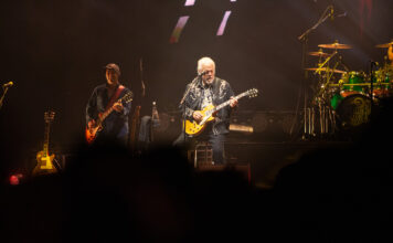 Bluesfest Day 9 review: The Guess Who closes Bluesfest with a powerful Canadian celebration Guy plays guitar on stage with other guitarist behind him.