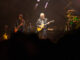 Bluesfest Day 9 review: The Guess Who closes Bluesfest with a powerful Canadian celebration Guy plays guitar on stage with other guitarist behind him.