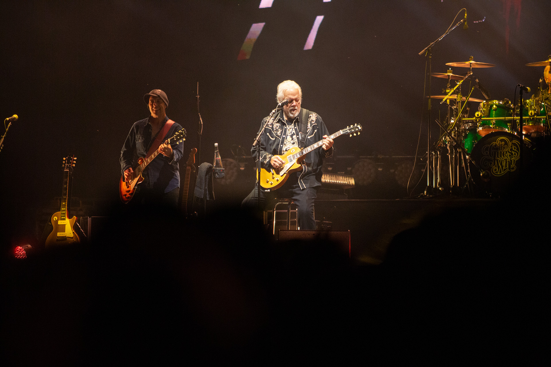 BF-J19-EF26 (1) Guy plays guitar on stage with other guitarist behind him.