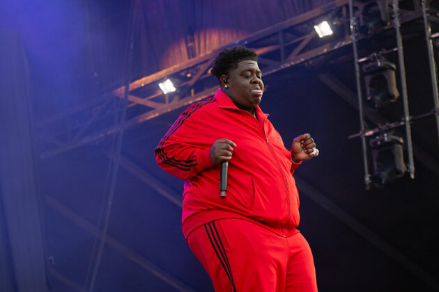 Man dances in red tracksuit on stage