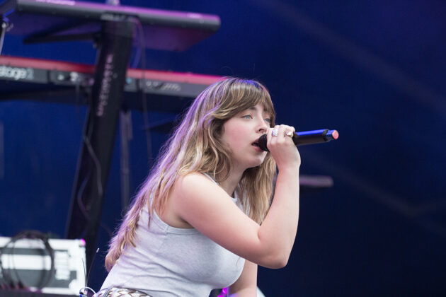 Woman sings into mic smiling slightly