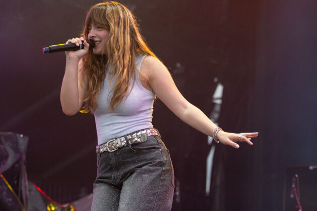Woman grins while singing into handheld mic