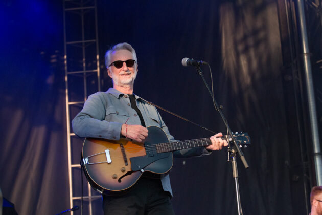 Man with sunglasses plays guitar and sings