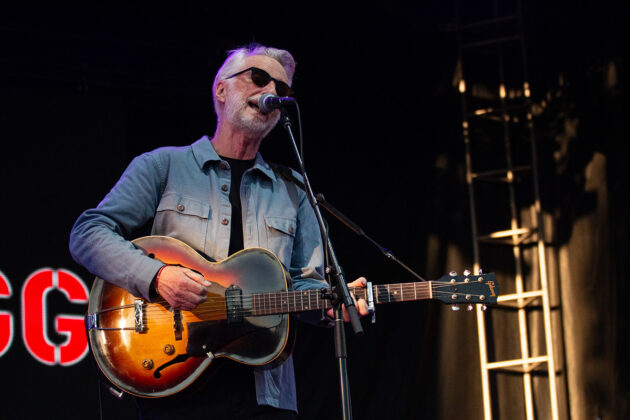 Man with sunglasses plays guitar and sings