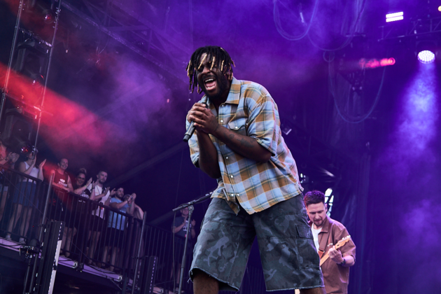 Man leans into mic while singing on stage