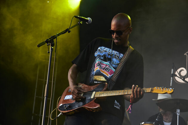 Man wearing sunglasses plays guitar on stage
