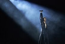 Bluesfest Day 5 review: Conan Gray dazzles at Bluesfest Man wearing black outfit stands in bright spotlight raising microphone to air