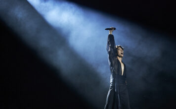 Bluesfest Day 5 review: Conan Gray dazzles at Bluesfest Man wearing black outfit stands in bright spotlight raising microphone to air
