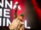 Bluesfest Day 2 review: Limp Bizkit brings the house down with metal nostalgia and a hometown surprise Man raises arm with microphone on stage with song lyrics behind him