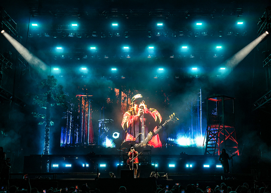 GregKolzHardy Man sings on massive stage with projector behind him