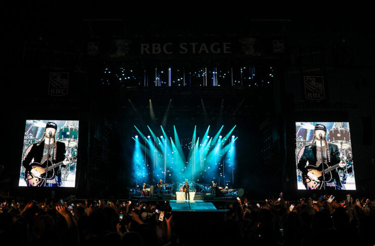 Bluesfest Day 4 review: The Lumineers close out a genre-spanning Sunday to a jam-packed audience Massive crowd at LeBreton flats in front of RBC Stage with bright screens and lights illuminating band on stage