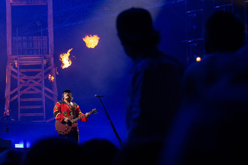 Musician sings in direction of fans on shoulders of one another