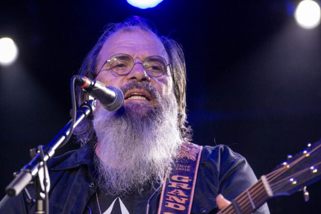 Man looks up at crowd while singing and playing guitar