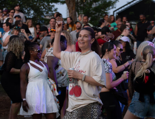 Person dances while holding a drink amongst a crowd