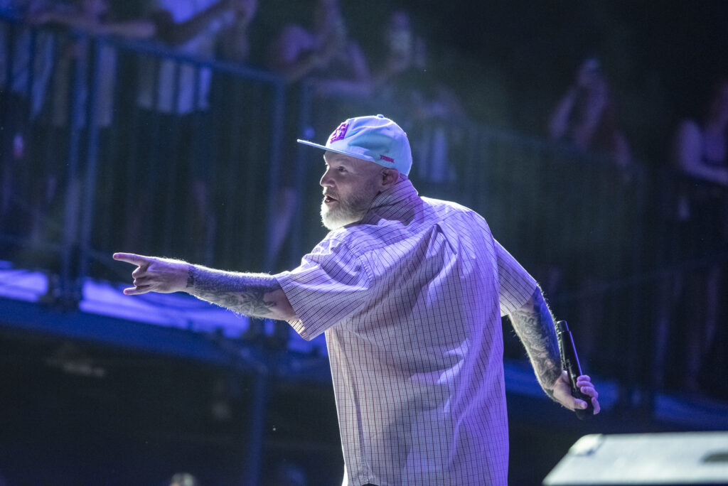 Man points out at crowd on stage with baseball cap on
