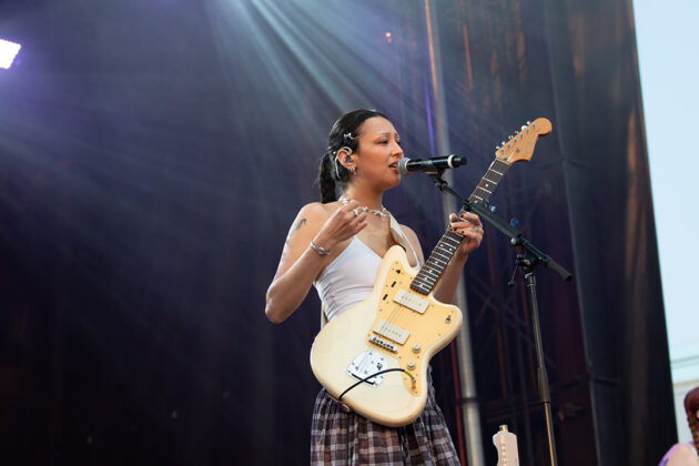 Woman sings with guitar strapped around her