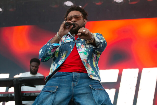Man points at camera while singing into mic